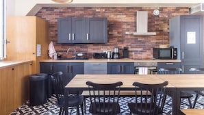 A modern kitchen with a brick backsplash, dark cabinets, and a wooden dining table with black chairs. - PHILIPPE AUGUSTE LOFT 4 - Loft for 12 - 5 rooms - BASTILLE - PÈRE LACHAISE (Paris)