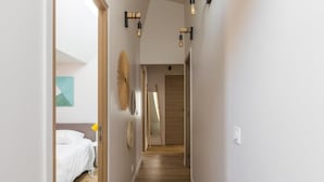 A narrow hallway with wooden flooring, a bed with white bedding, and a door at the end. - PHILIPPE AUGUSTE LOFT 4 - Loft for 12 - 5 rooms - BASTILLE - PÈRE LACHAISE (Paris)