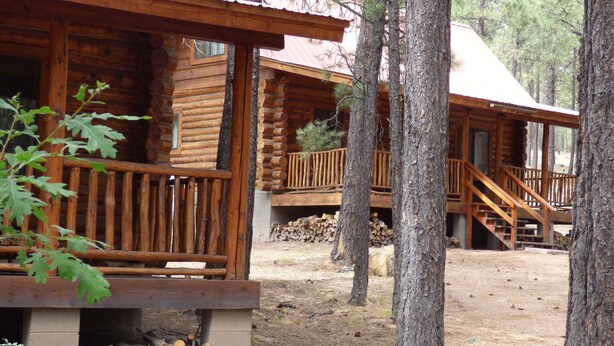 Un chalet rustique doté d’une terrasse en bois et d’un foyer extérieur.
