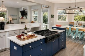 A modern kitchen with a central island, a dining area with a table and chairs, and a view of the outdoors. - Beautiful 2nd Row Home, Steps to the Beach, Close to Coligny Private Pool Hot Tub (HIlton Head)