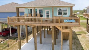 A two-story wooden structure with a balcony, a door, and a sign indicating it is a rental property. - Blue Water Escape - 3 bedroom, 2 bath home that sleeps 8 - Easy Beach Access! (Crystal Beach)
