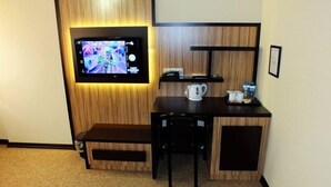 A compact room with a television mounted on a wooden panel wall, a small table with a kettle, and a bench. - Ridvan Otel (Bursa)