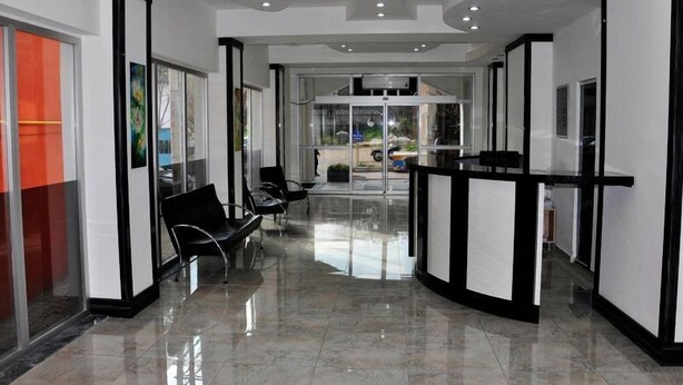A modern hotel lobby with a reception desk, seating area, and glass doors leading outside. - Ridvan Otel (Bursa)