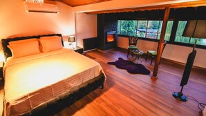 Ein Schlafzimmer mit einem großen Bett, einem Kamin und Blick ins Freie.