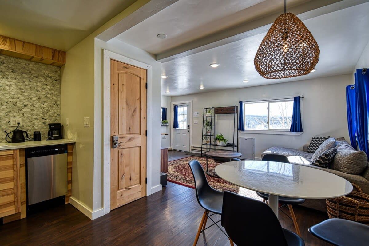 A modern kitchen with a dishwasher, wooden cabinets, and a stone backsplash.