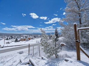 A snowy landscape with a clear sky, a fenced area with snow-covered trees, and a distant view of buildings and mountains. - The Hilltop Suite — Mt Massive Views | Pet OK | EV Charger | Sleeps 4 (Leadville)