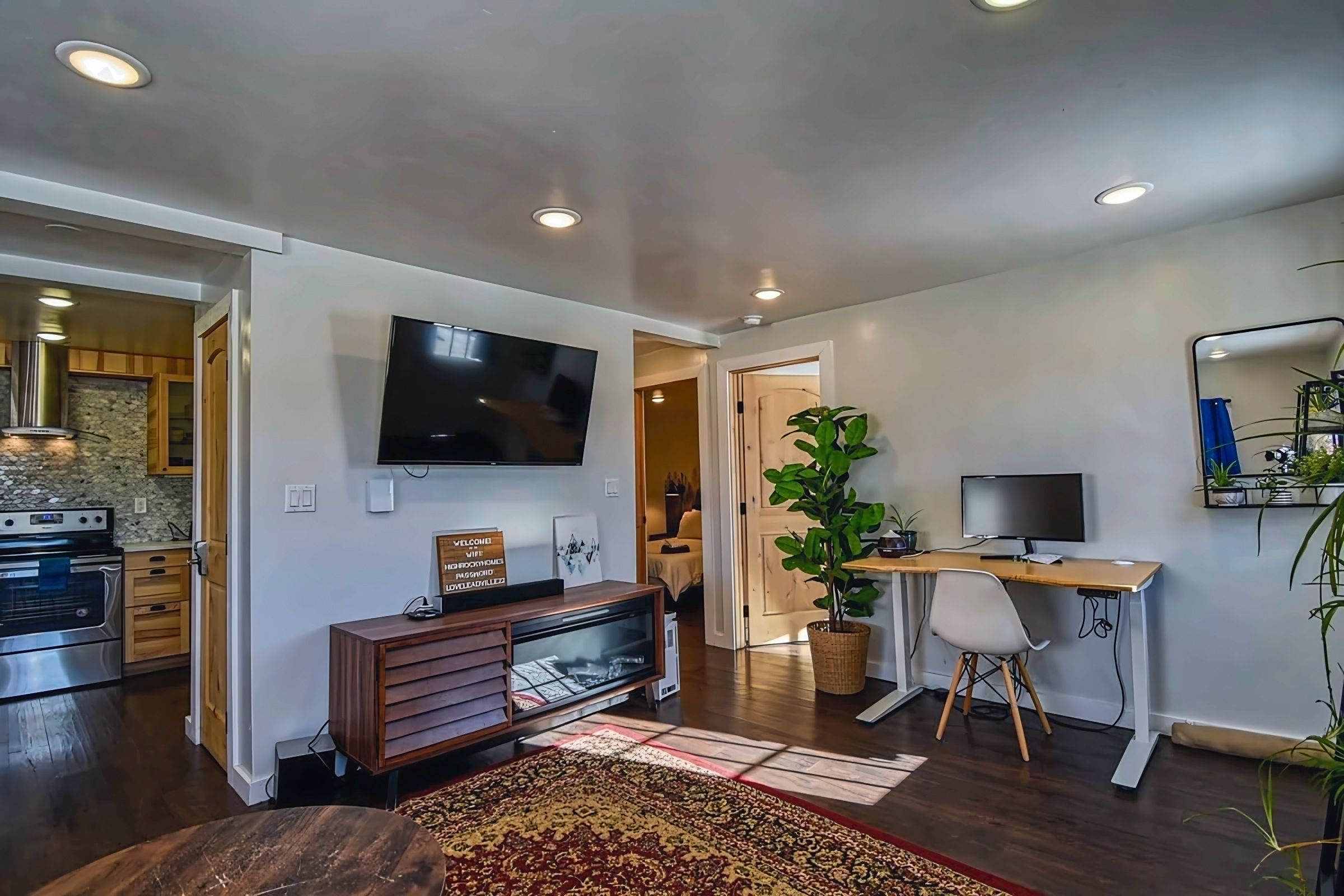 A modern living space with a kitchen, dining area, and a TV mounted on the wall.