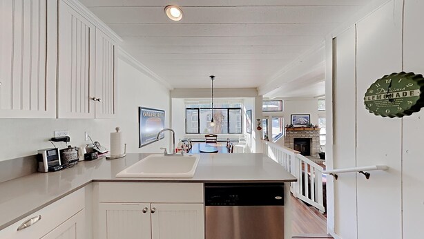 A kitchen with white cabinetry, a stainless steel dishwasher, and a window overlooking a cityscape. - Spacious 2 Bedroom Home with Pool, 3 Hot Tubs, Sauna! by RedAwning (Mammoth Lakes)