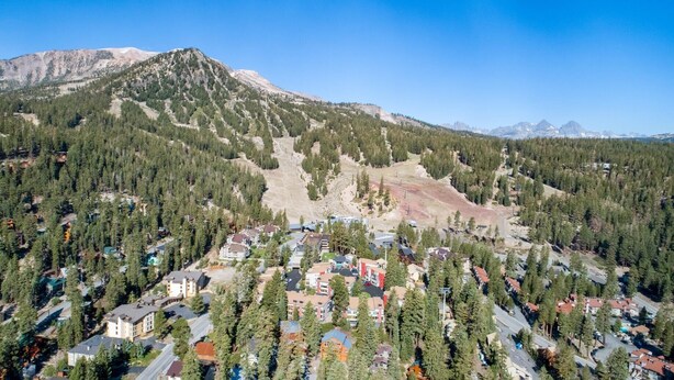 A residential area with houses surrounded by dense forests and mountains in the background. - Slopeside Remodeled 2 Bedroom Condo with Amazing Views! by RedAwning (Mammoth Lakes)