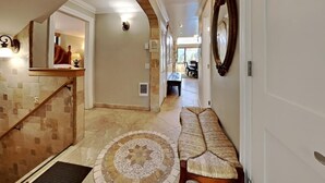 A hallway with a tiled floor, a bench, a staircase, and a dining area in the distance. - Deluxe Condo with Fireplace (Unit 623 at 1849) (Mammoth Lakes)
