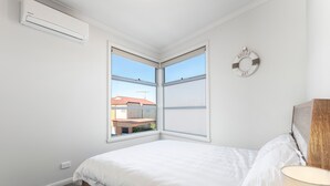A bedroom with a bed, a window, and an air conditioning unit. - Bay & Relax (Apollo Bay)