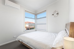 A bedroom with a bed, a window, and an air conditioning unit. - Bay & Relax (Apollo Bay)