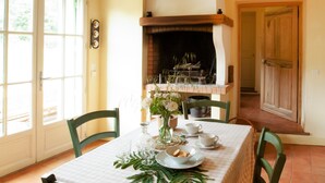 A dining room with a table set for two, a fireplace, and a view through a window. - Beautiful country house [29+ guests], with swimming pool, facing the Colorado (Rustrel)