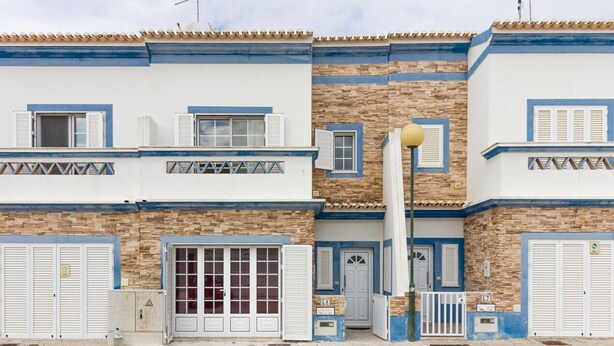A multi-story building with a stone facade, blue trim, and white shutters.