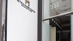 L'ingresso di un hotel con una porta in vetro, un cartello con la scritta "PIETRA MARE SUITES DOWNTOWN LIVING" e un corridoio con pavimento decorato.