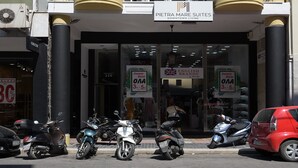 Un edificio a più piani con balconi, un cartello con la scritta 'PIETRA MARE SUITES' e scooter parcheggiati.