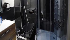 Un bagno moderno con cabina doccia in vetro, pavimento in piastrelle bianche e nere e un mobile vanitario in legno con specchio.
