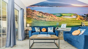Ein Zimmer mit einem großen Wandgemälde eines Golfplatzes, einer blauen Sofagarnitur, einem Couchtisch und einem Schild mit der Aufschrift 'Sandy Toads & Silty Toads'.