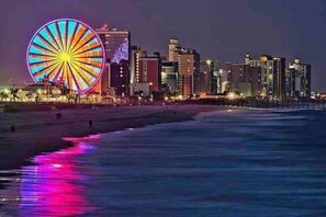 A coastal cityscape with a prominent Ferris wheel and high-rise buildings.