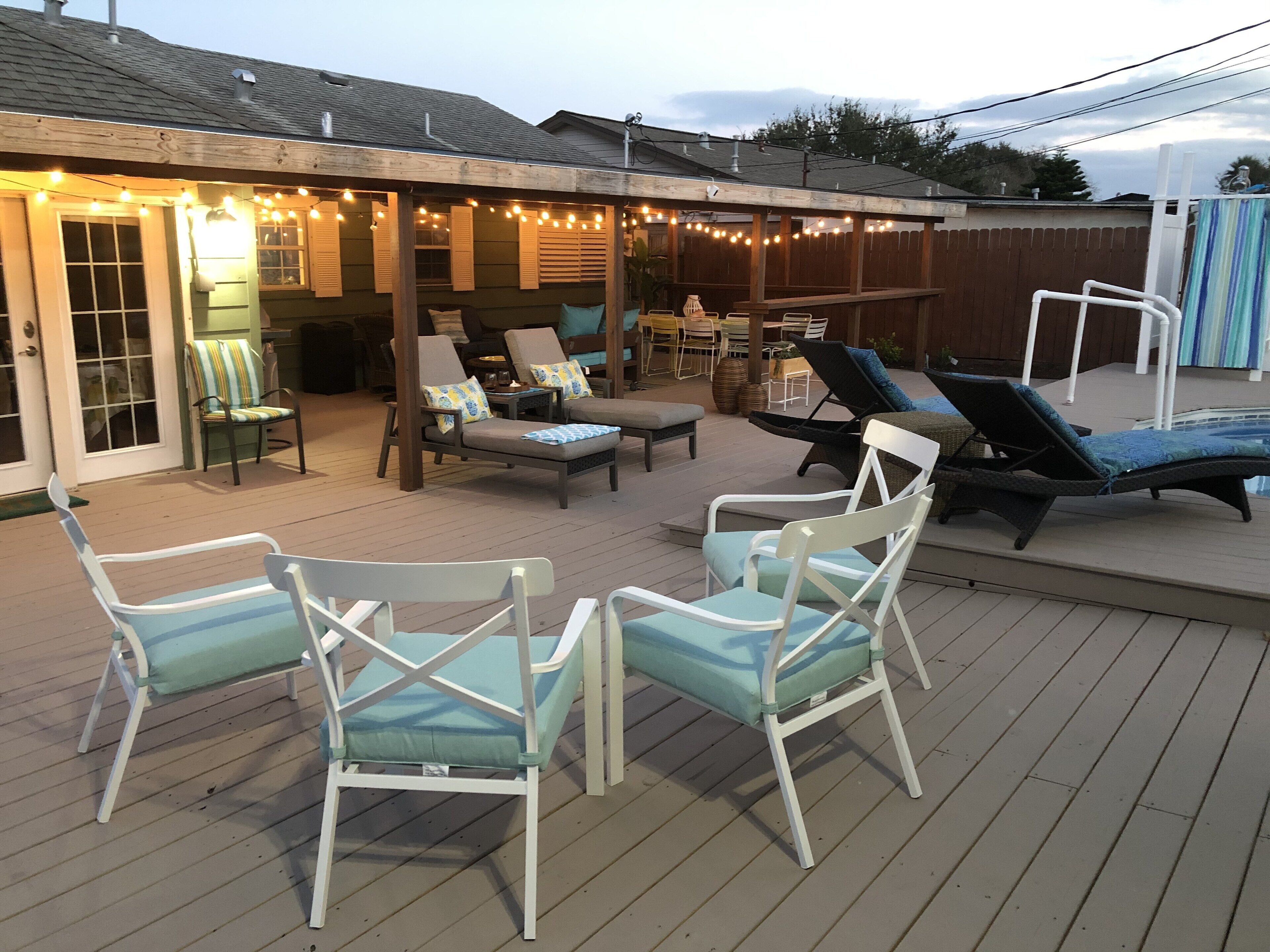 An outdoor deck with lounge chairs, a dining area, and string lights.