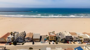 Una zona residenziale costiera con case lungo la spiaggia, un cielo sereno e l'oceano sullo sfondo.
