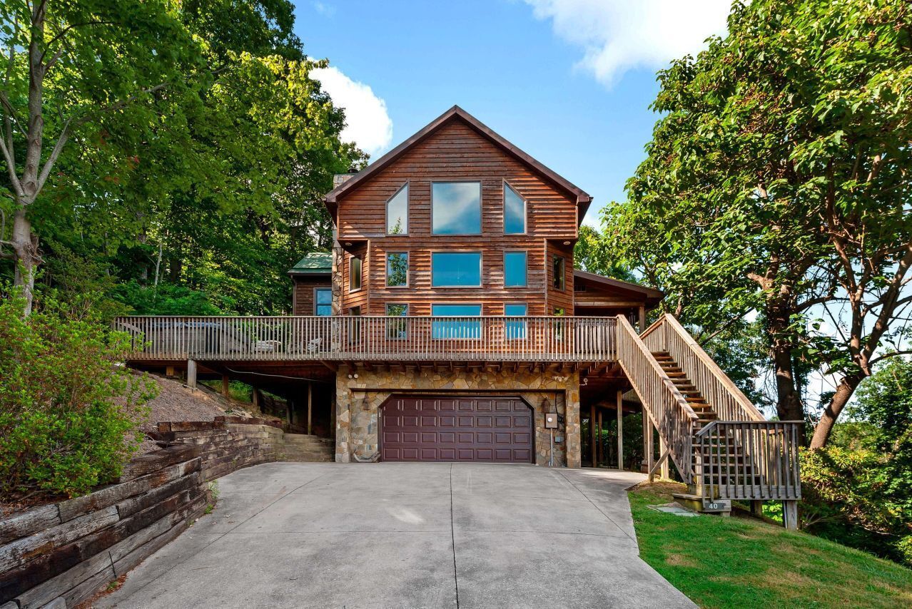 A two-story wooden house with a stone foundation, a covered front porch, and a garage.