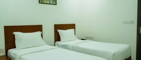 Habitación de hotel con dos camas individuales, ventilador de techo, un cuadro en la pared y suelo de madera.