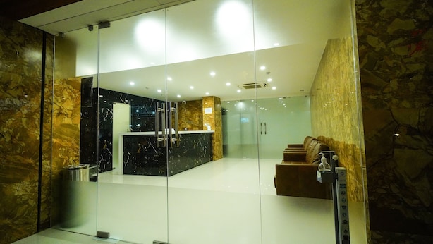 A modern lobby with a reception desk, glass doors, and a seating area with a sofa.
