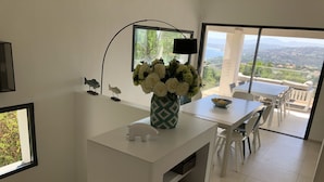 Eine moderne Küche mit weißen Schränken, einer weißen Blumenvase und Blick ins Freie.