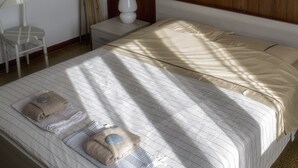 Una cama bien hecha con ropa de cama a rayas, una lámpara de noche y un panel de pared de madera.