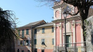 Un edificio histórico con un patio adoquinado, un muro de piedra y un árbol.