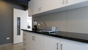 Una cocina moderna con armarios blancos, encimera negra y licuadora integrada.