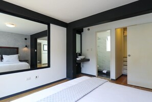 A modern bedroom with a large mirror, a bed, a built-in wardrobe, and a bathroom with a shower and toilet. - w* | Dreamy 3BR in Barranco (Barranco)