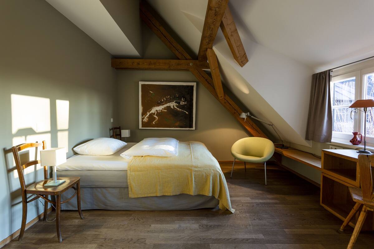 Une chambre à coucher avec un lit, un bureau, une chaise et une fenêtre.