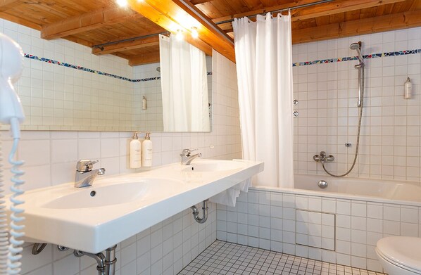 Un baño con dos lavamanos, una ducha e inodoro.