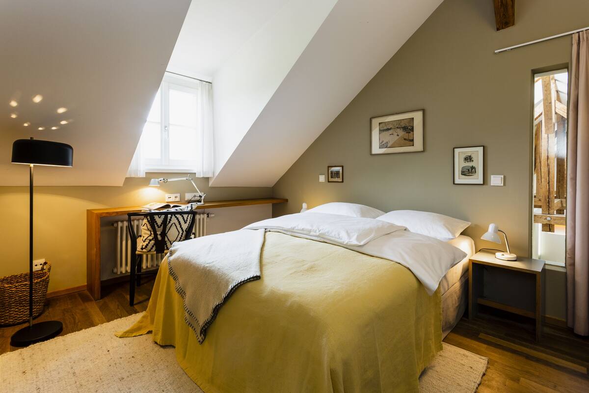 Une chambre à coucher avec un lit, des tables de chevet, un bureau et une fenêtre.