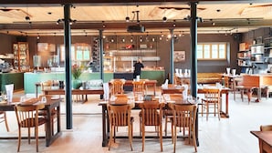 A restaurant with wooden tables and chairs, a bar area, and a counter with a menu. - Gut Sonnenhausen (Glonn)