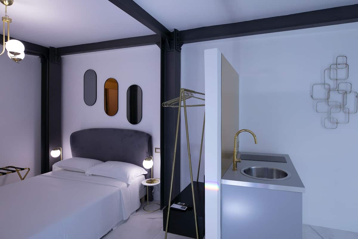 Un dormitorio moderno con cama, lámparas de noche, tocador con lavabo y espejos montados en la pared.