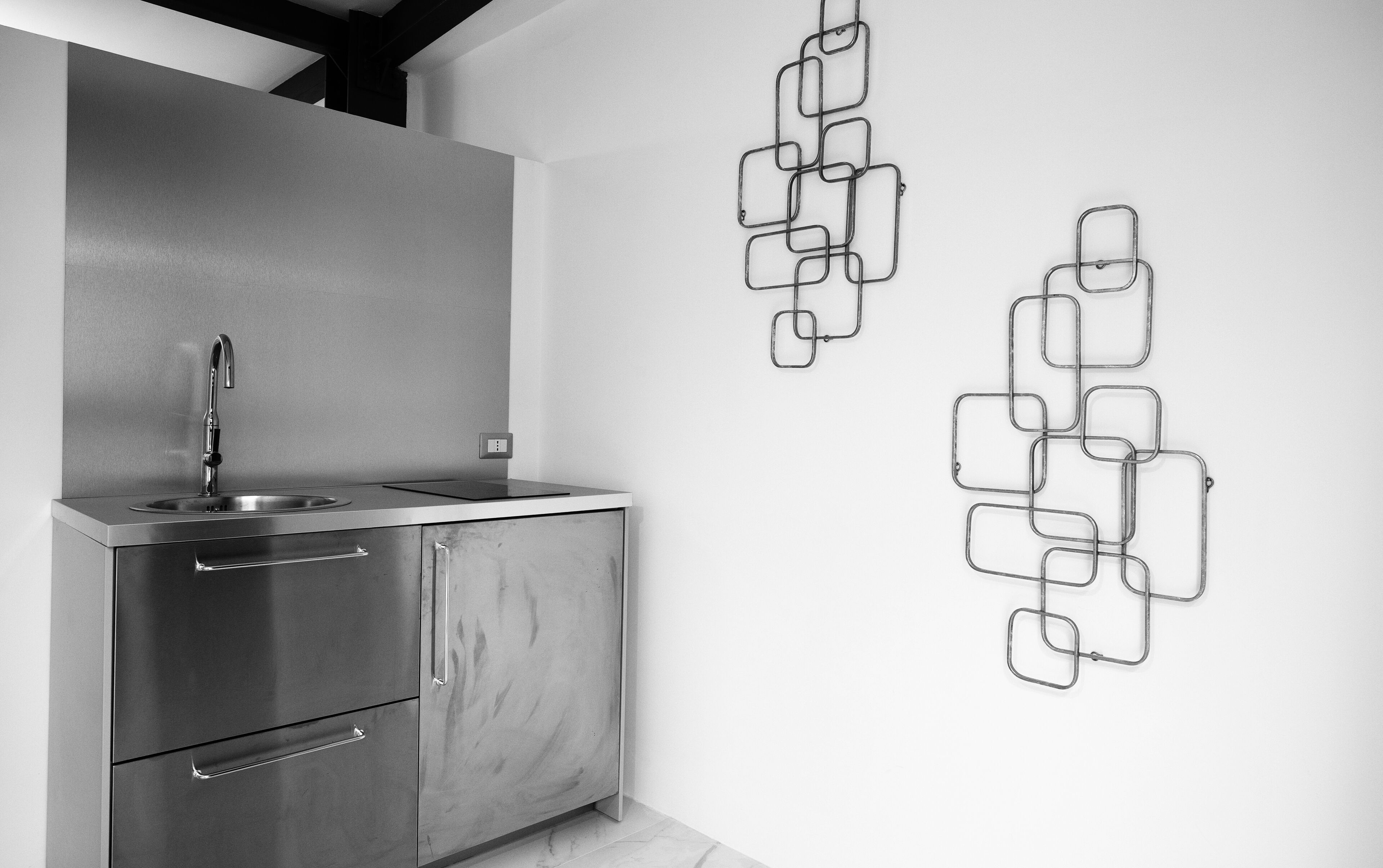 A modern kitchen with a stainless steel sink, a built-in oven, and a marble countertop.