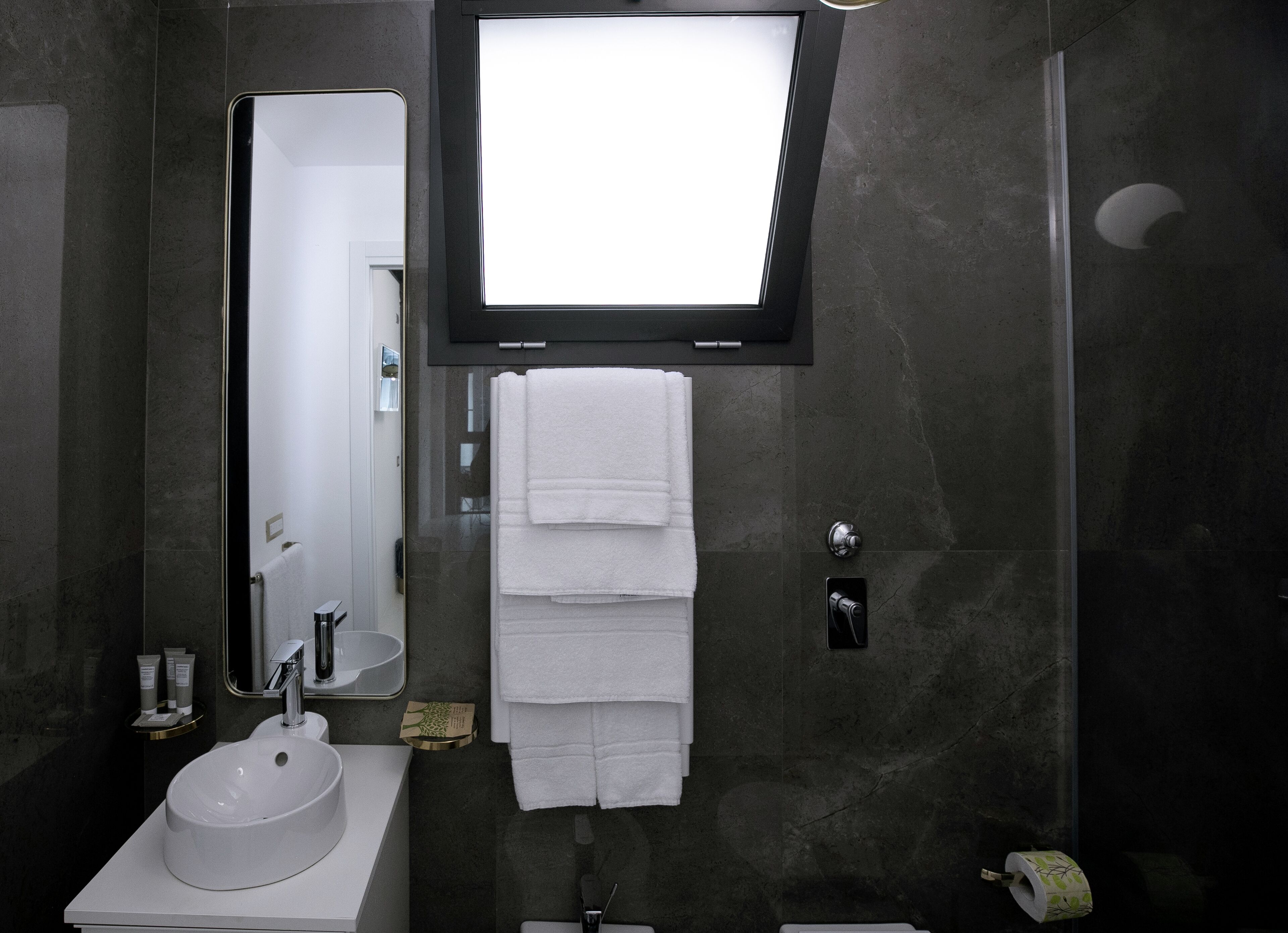 A modern bathroom with a large mirror, a sink, and a shower.