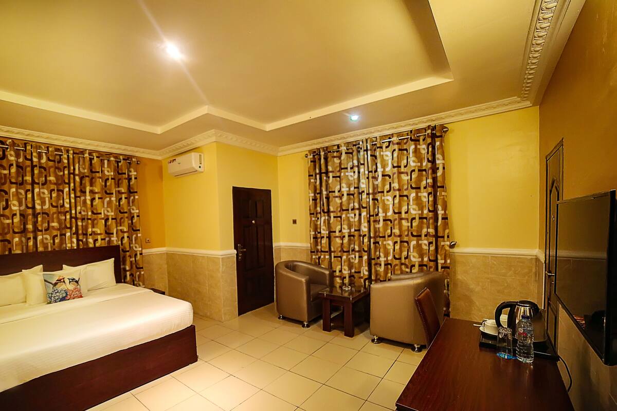 Een hotelkamer met een bed, een bureau, een stoel, een televisie en een badkamer met douchegordijn.