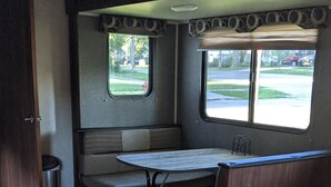 Interior de una caravana compacta con kitchenette, zona de estar y ventanas.