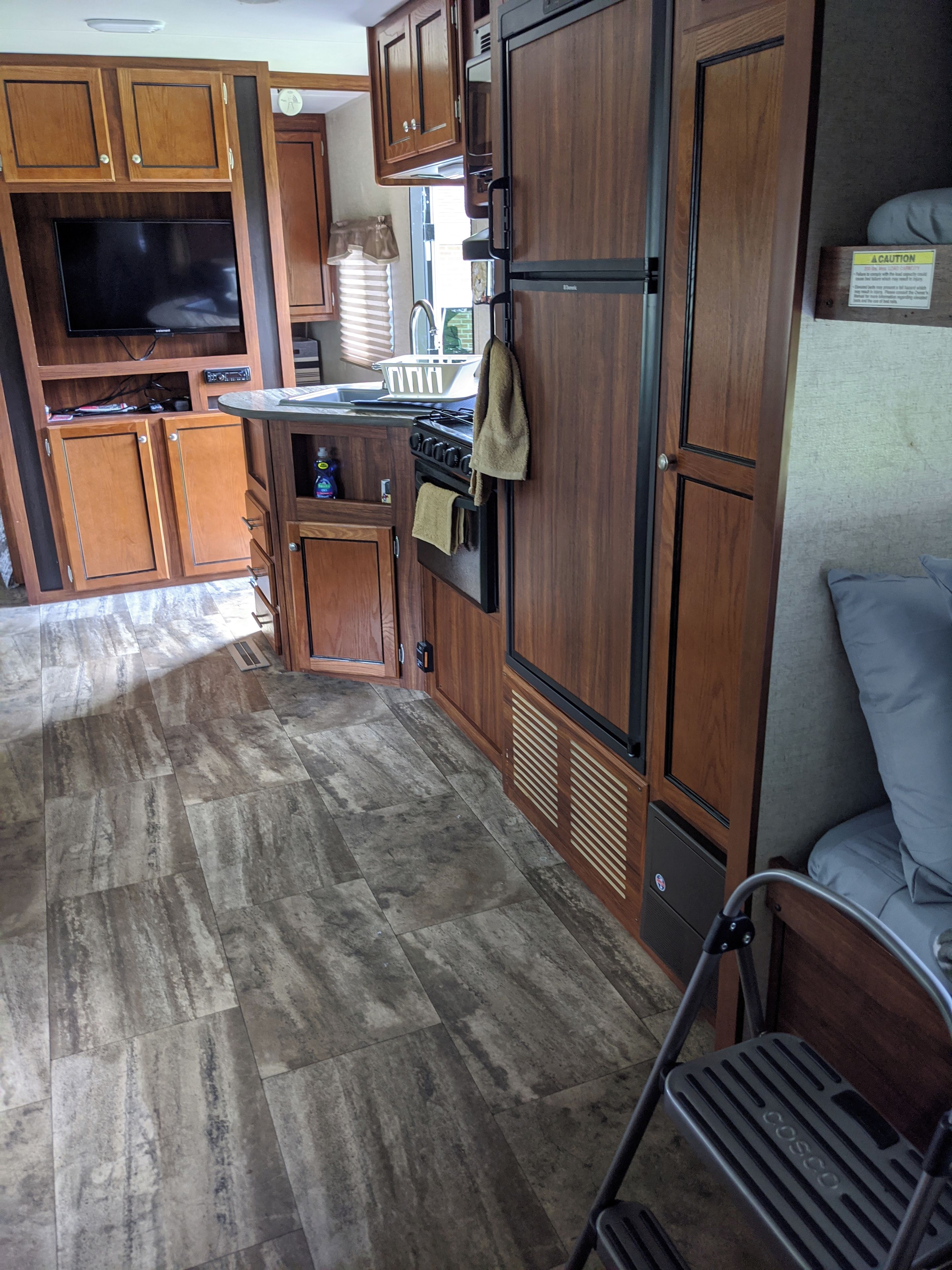 Interior d'una caravana compacta amb una petita cuina, zona de seients i una finestra.