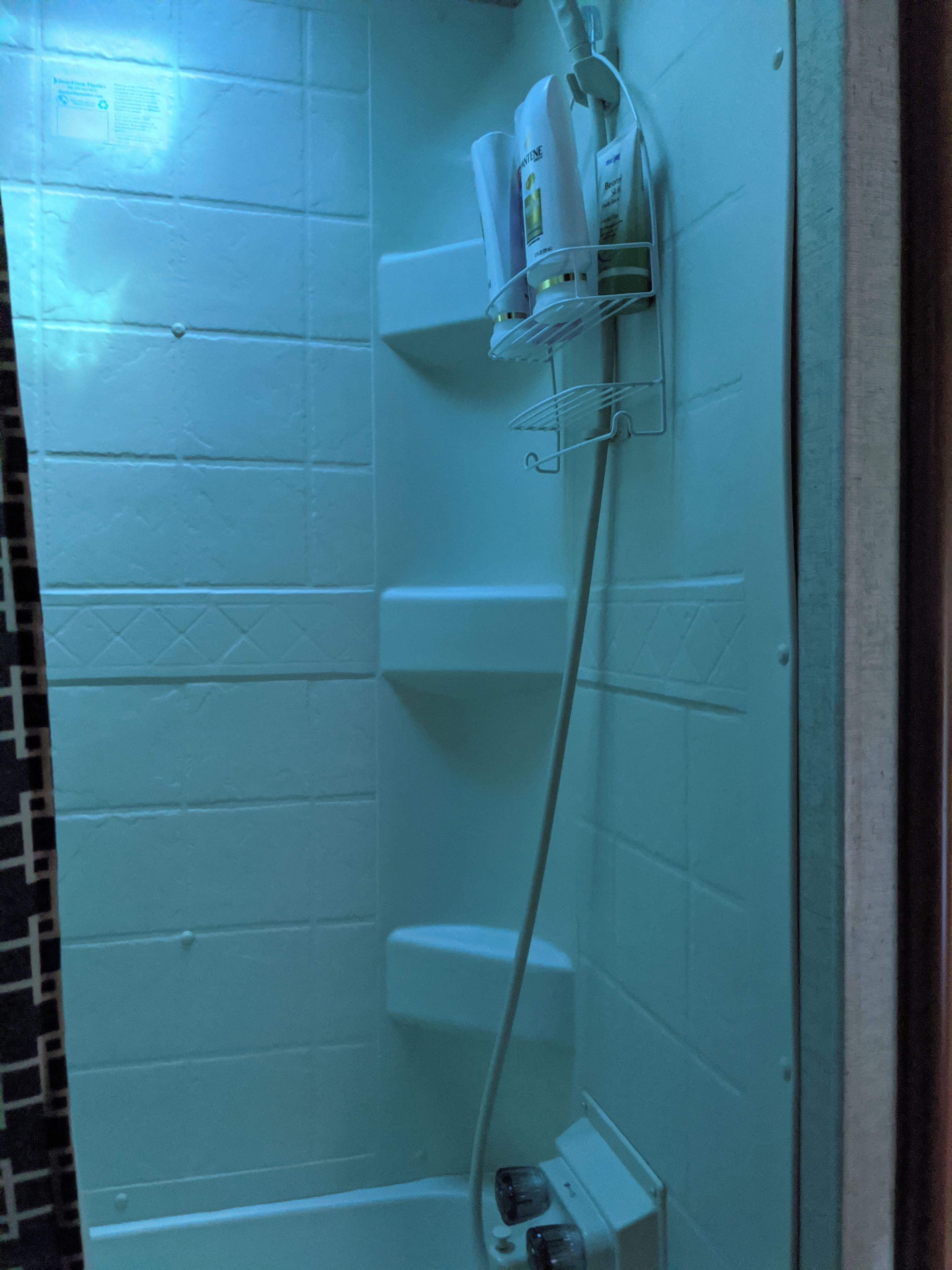 A bathroom with a glass partition, a towel rack, and toiletries on the counter.