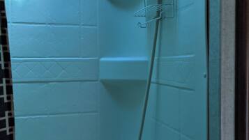 A bathroom with a glass partition, a towel rack, and toiletries on the counter.