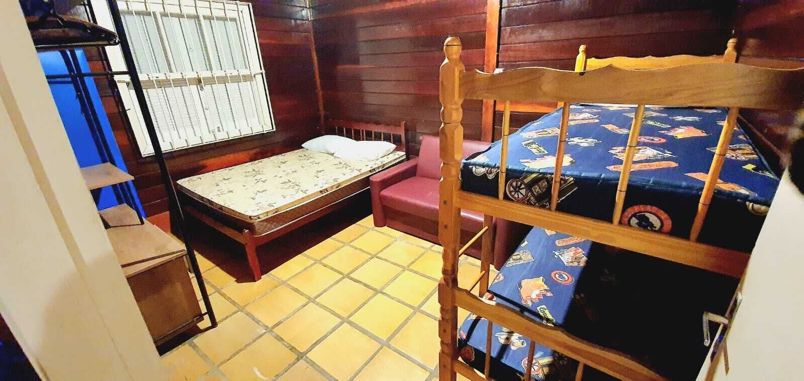 Une petite pièce, de taille modeste, comprenant un lit superposé, un lit simple et une fenêtre grillagée.