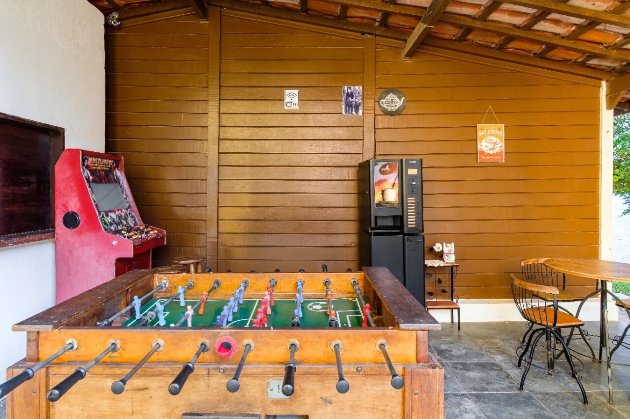A foosball table, a coffee machine, and a table with chairs in a wooden room.