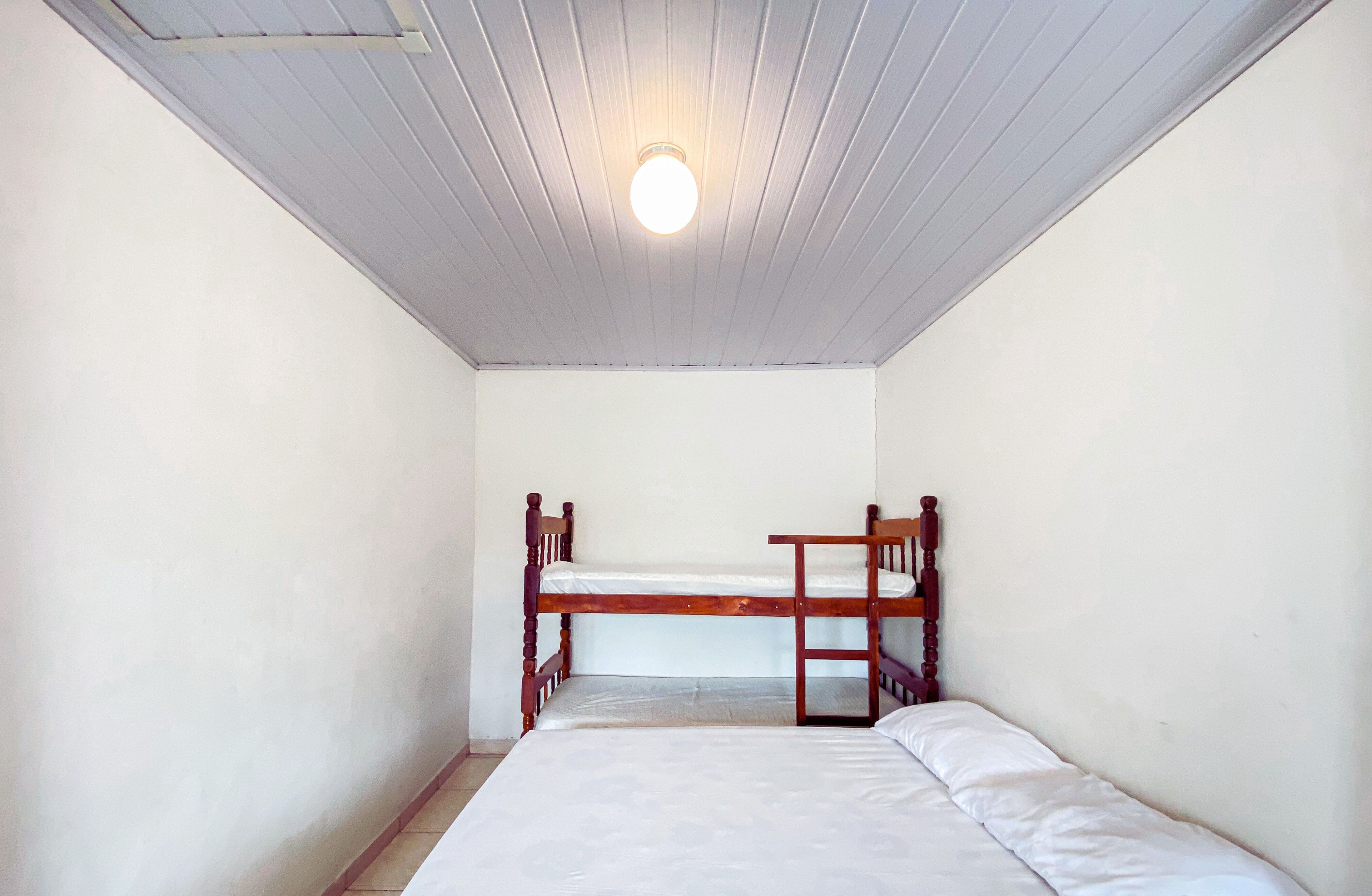 A small, single-room accommodation with a bunk bed and a single bed.