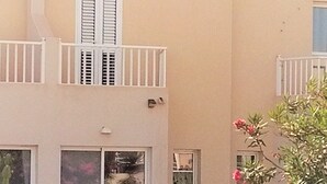 Un immeuble à deux étages doté de balcons, de grandes fenêtres et d’une clôture blanche.