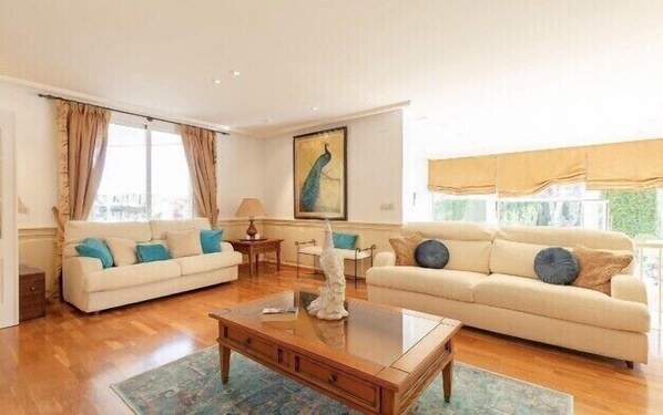 A living room with two sofas, a coffee table, and a painting on the wall. - Large Luxury Villa , with Large Gardens , pool ,gym and tennis court. (santa pola)